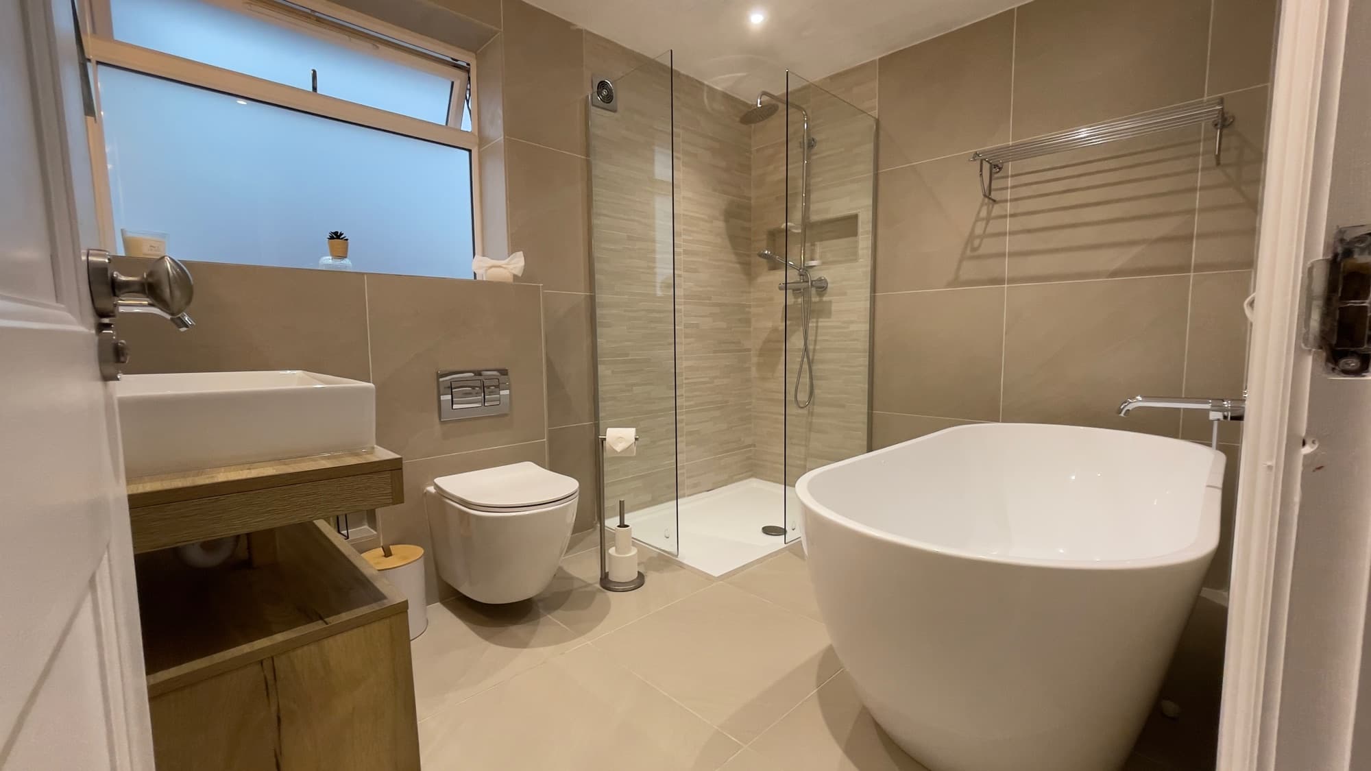 A bathroom with a freestanding bath and walk-in shower after a full clean