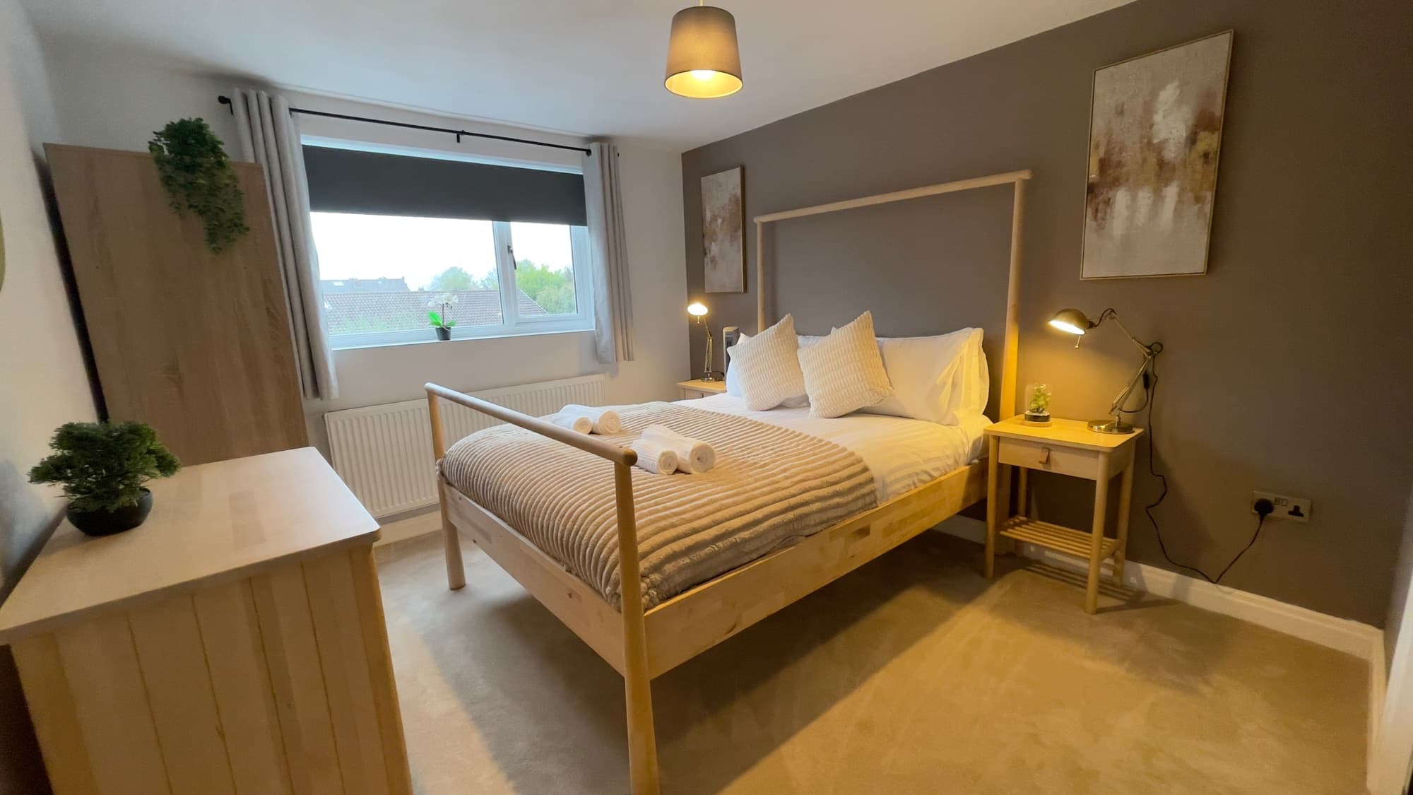 A bedroom made up to housekeeping standard, with white linen and rolled towels on the bed