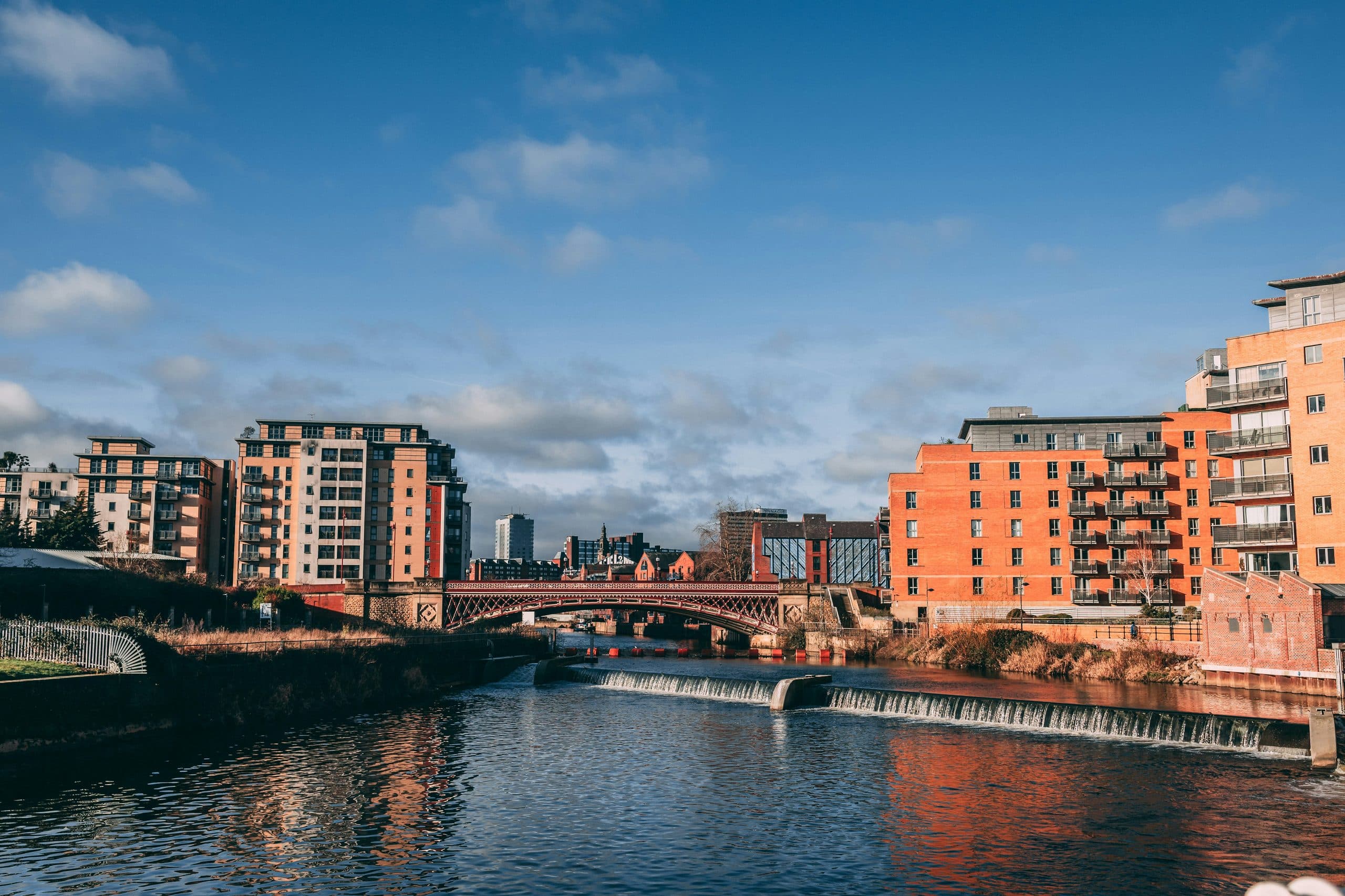 Riverside apartment blocks along the River Aire in Leeds, with the red Crown Point Bridge